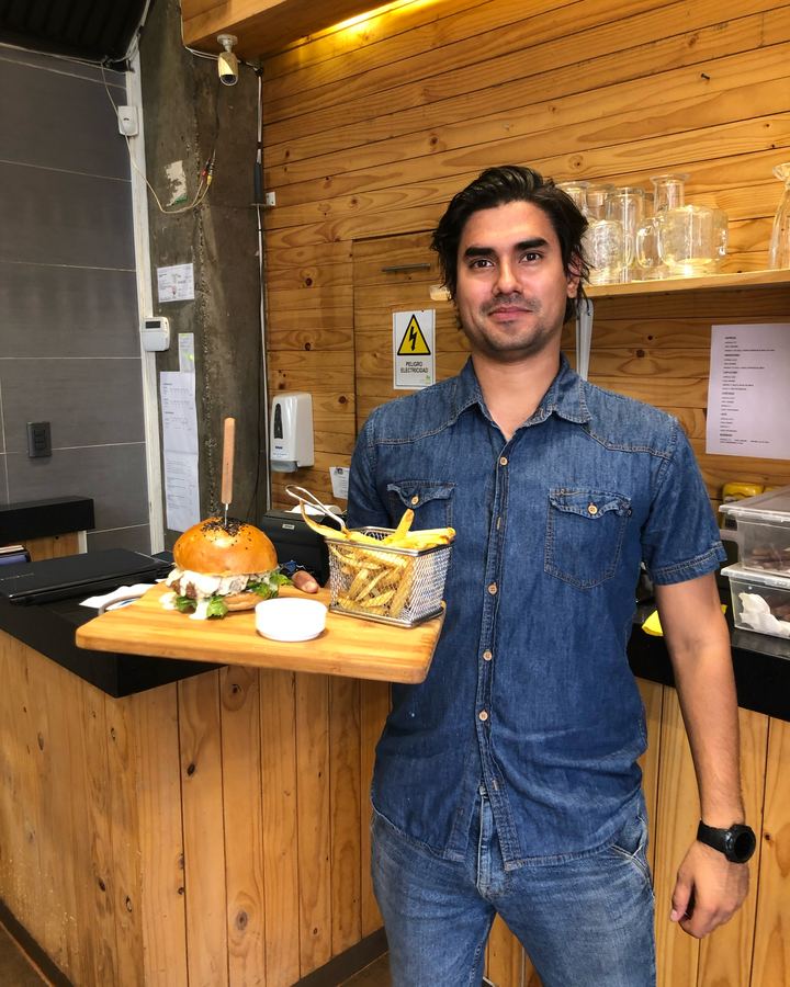 Elías en su hamburguesería de Santiago de Chile, con una hamburguesa y papas fritas.