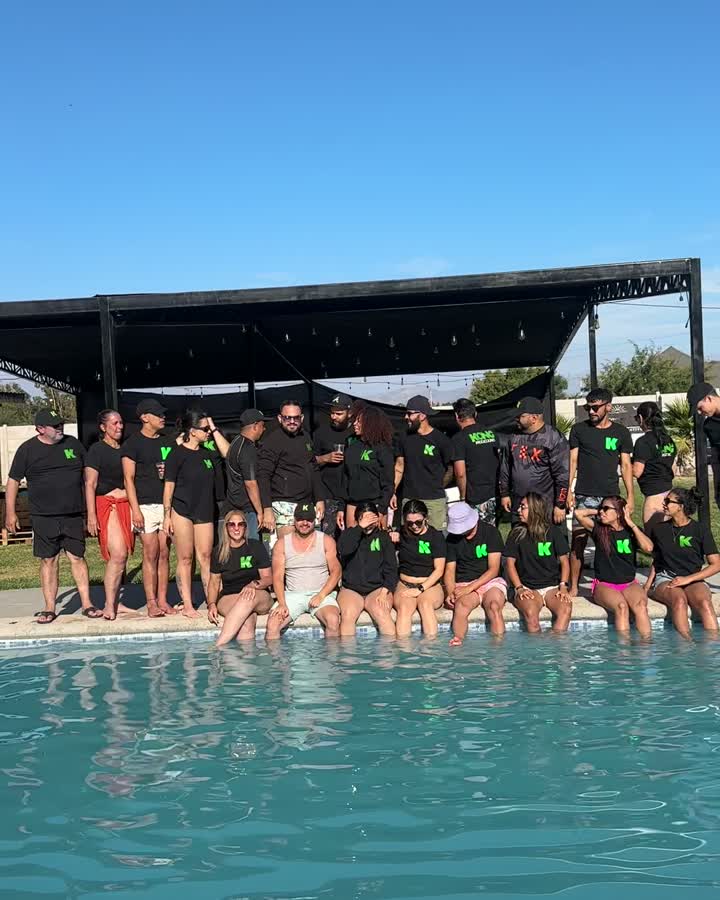 El equipo de Kong Producciones con poleras negras de la marca, reunido junto a una piscina.